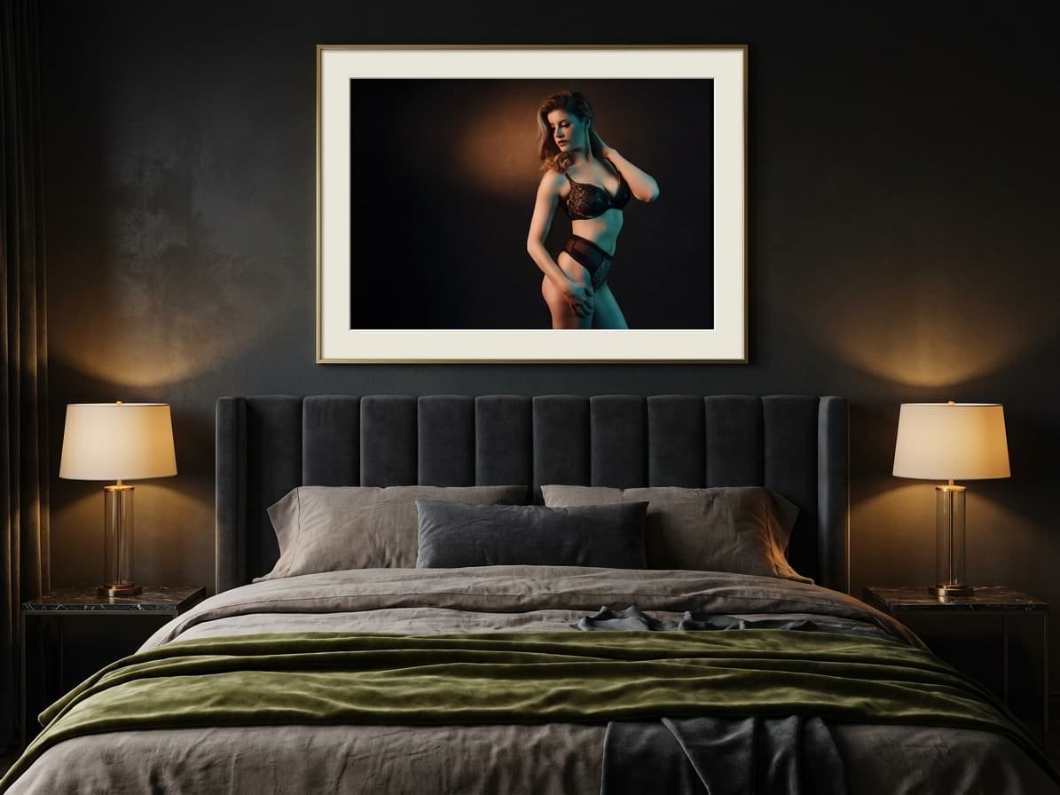 Framed fine art boudoir print hung above the bed in a dark, moody bedroom